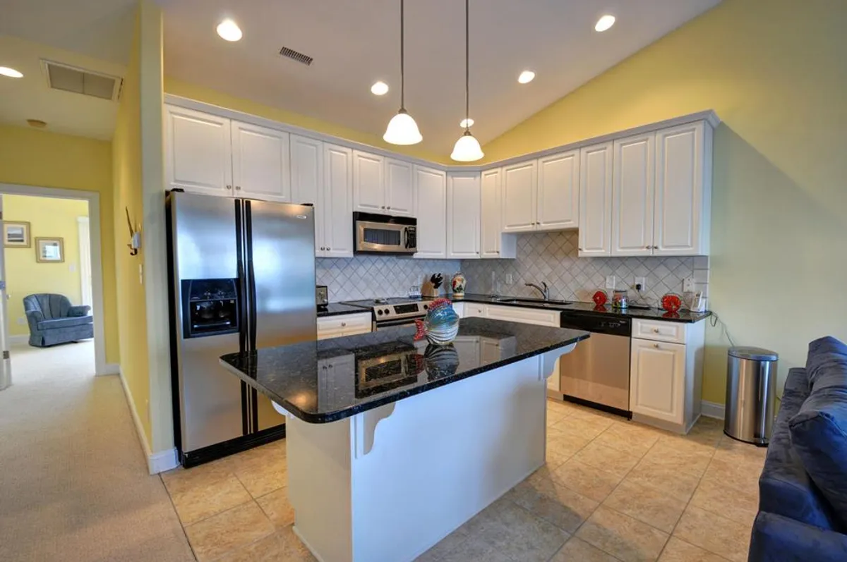 A bright, open-concept kitchen features a spacious granite countertop and sleek stainless steel appliances. Colorful decor accents add a cheerful touch, and the layout is ideal for cooking, entertaining, and enjoying family gatherings. The space feels modern but welcoming, with plenty of room for group activities.