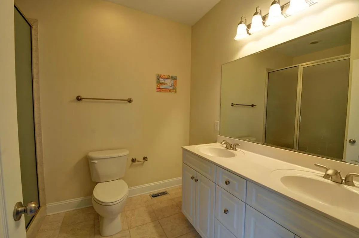 A spacious bathroom with a double vanity, a large mirror, and a glass shower enclosure. The space is bright and airy, ideal for personal grooming and refreshing after a beach day.